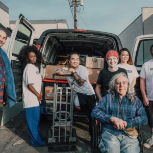 A diverse group of volunteers packing aid supplies into a van for donation.